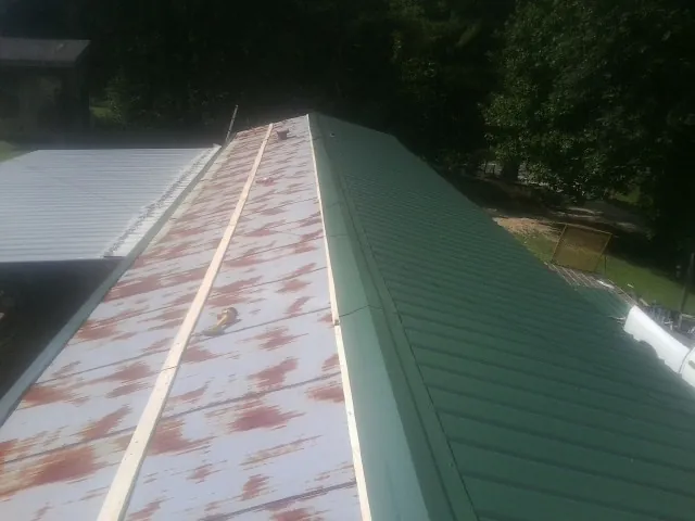 Old rusted panels beside newly installed green metal roofing — Wind Damage Roof Repair by Roofing Brothers in Kilbourne