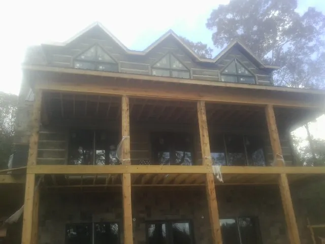 Dormers and porch framing on a large log home under construction — Roof Coating work by our crew in Kilbourne