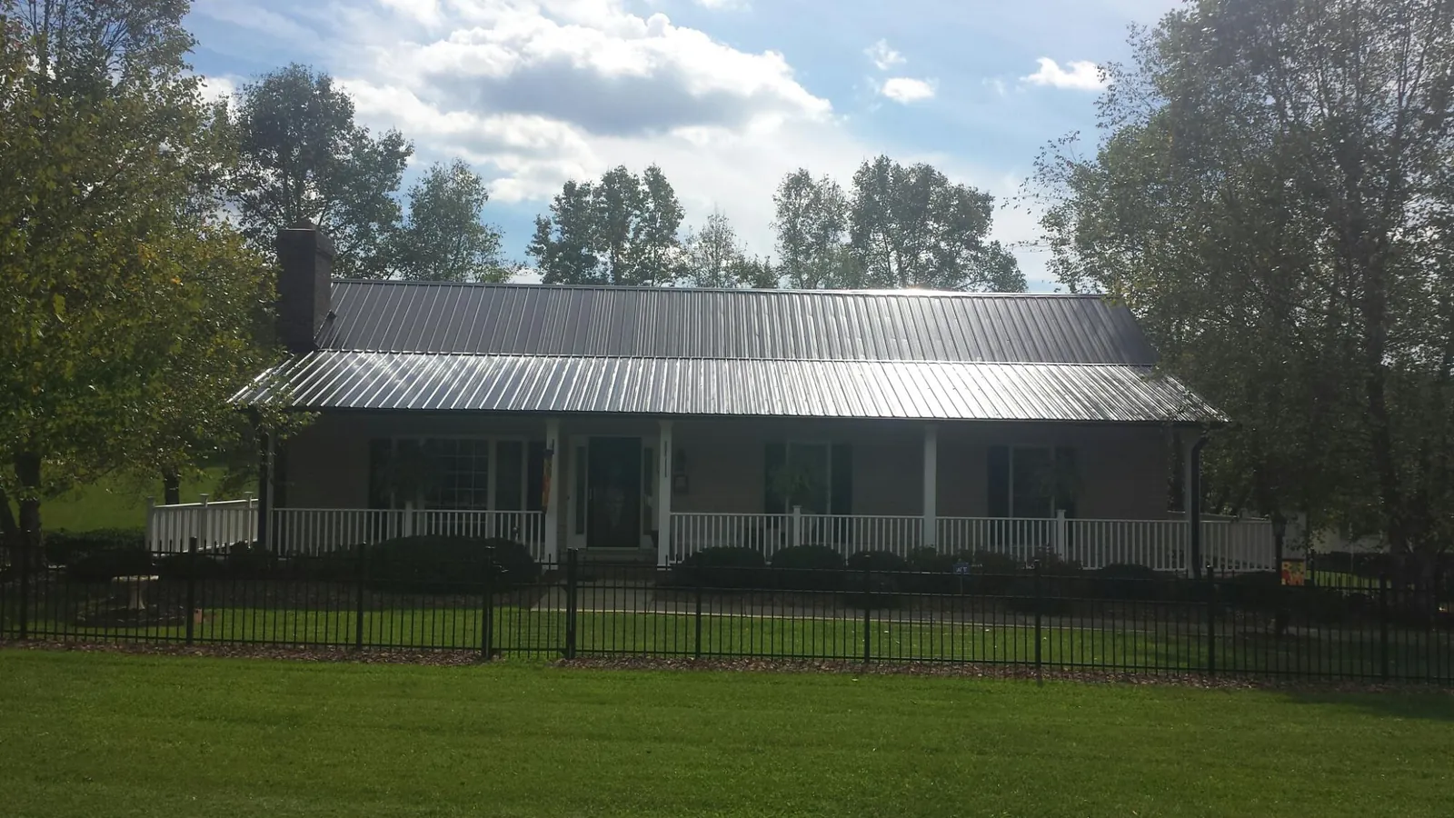 Gray metal roof on a brick ranch with a full width front porch — Gutter Guard Installation work by our crew in Kilbourne