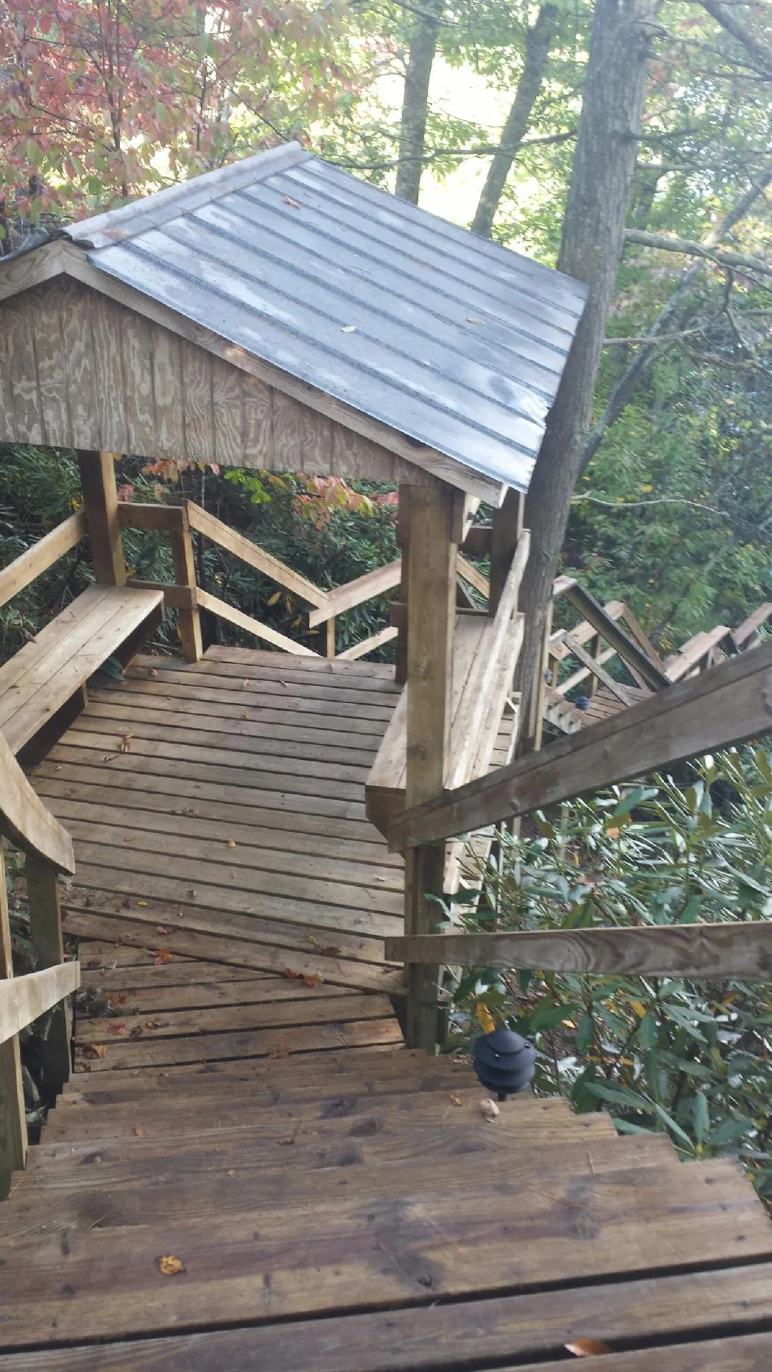 Metal roofed shelter over wooden steps on a wooded walkway — Skylight Repair & Installation work by our crew in Kilbourne