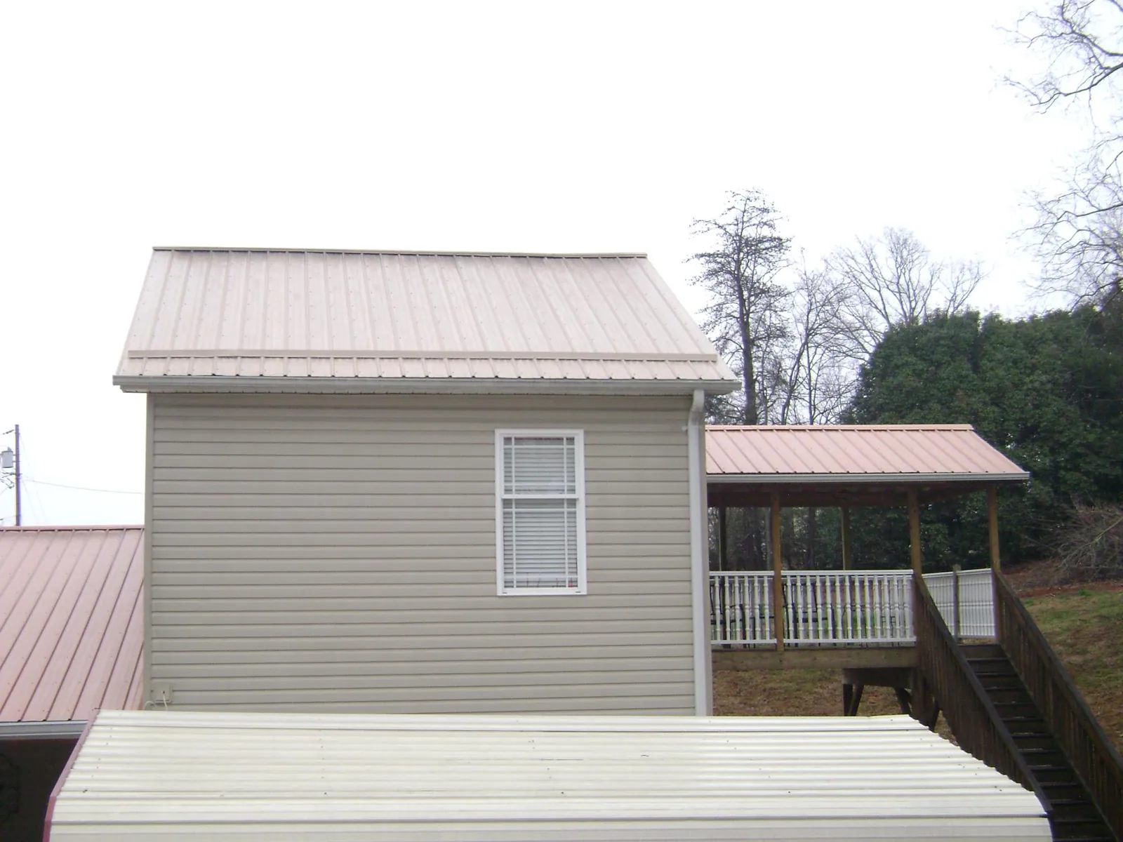 Tan metal roofs on a two story addition and attached porch, from a Roof Replacement job in Kilbourne